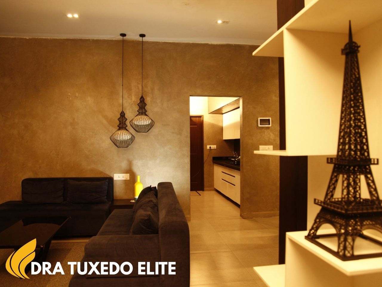 Modern model flat interior at DRA Tuxedo Elite in Chennai showcasing premium living room design with warm lighting and open kitchen layout.