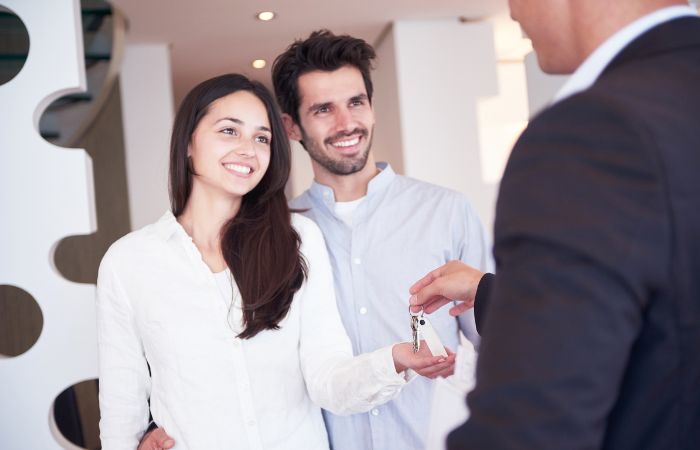 A woman happily collecting her home key from a property developer. Her husband is standing beside her.