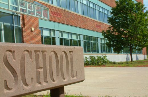 Facade of a school building adorned with a sturdy board that proudly displays the word SCHOOL