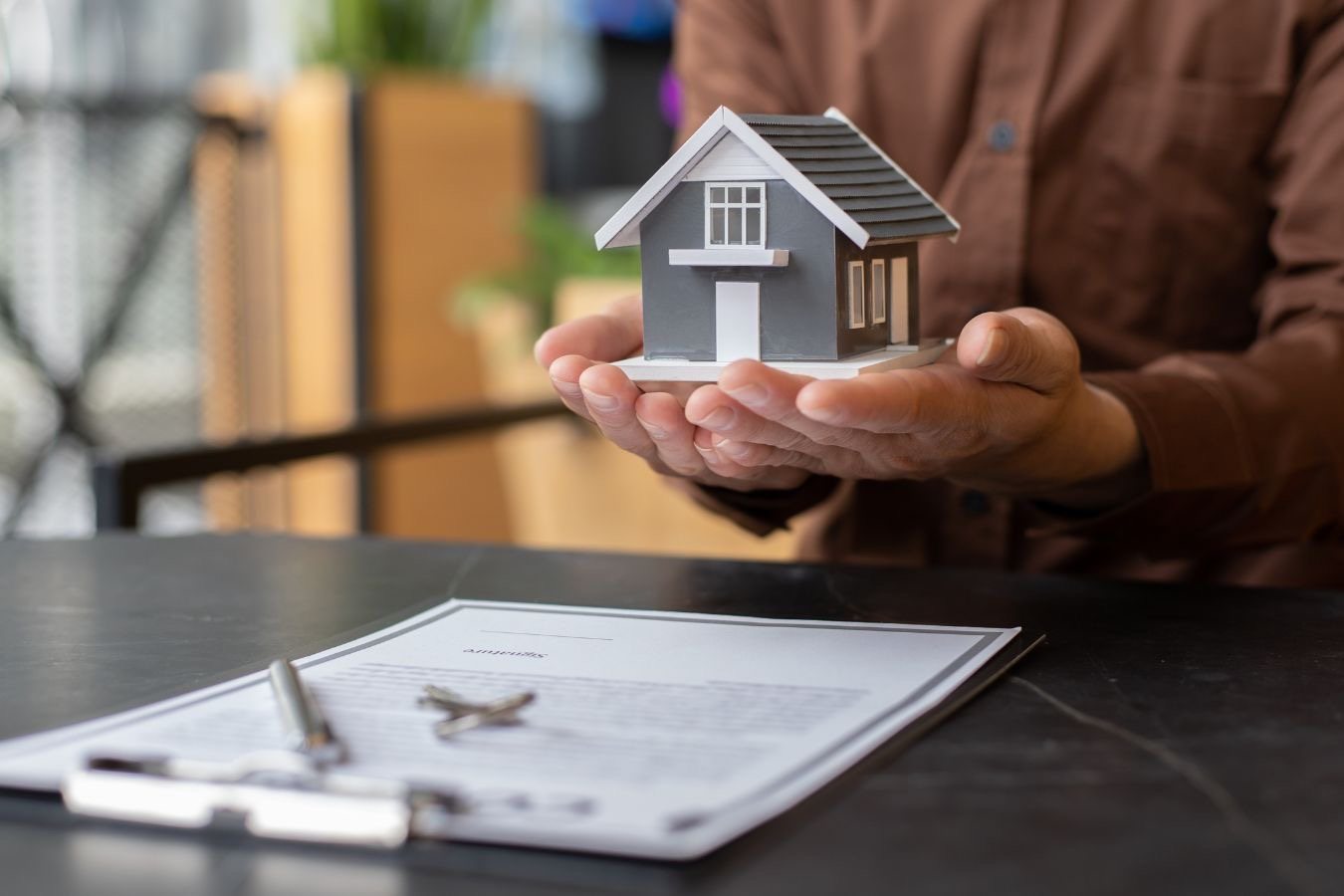 A man holding a miniature house in both hands