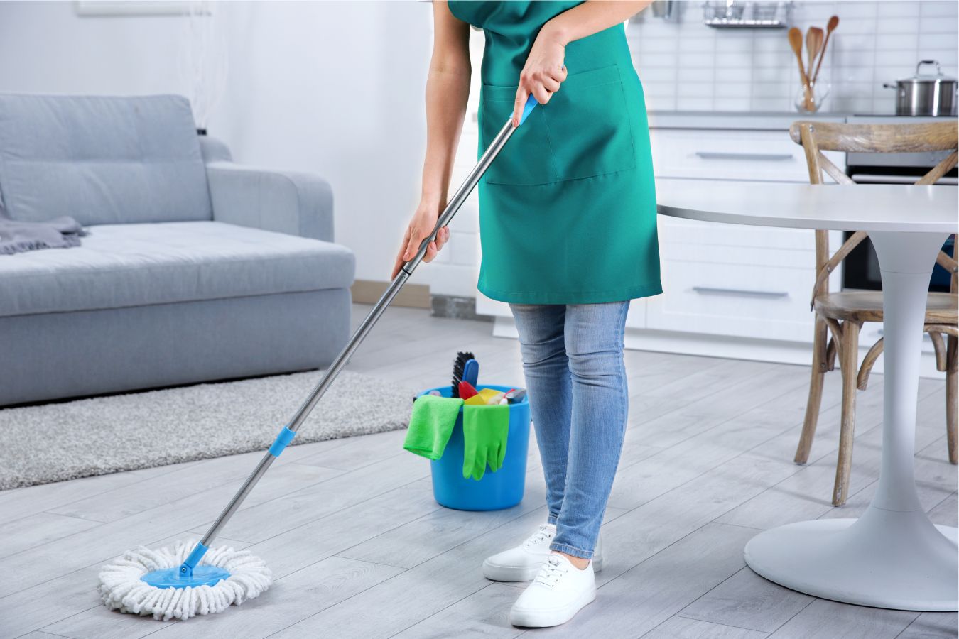 A lady cleaning the home with a bucket of cleaning liquid and mop