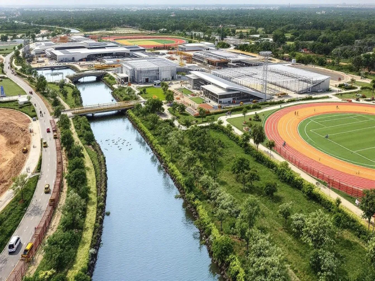 The image depicts the ongoing construction of the Global Sports City in Semmancheri, Chennai, showcasing various sports infrastructure, including football fields, cycling tracks, and rowing facilities, alongside sustainable urban design elements like water channels for flood management.