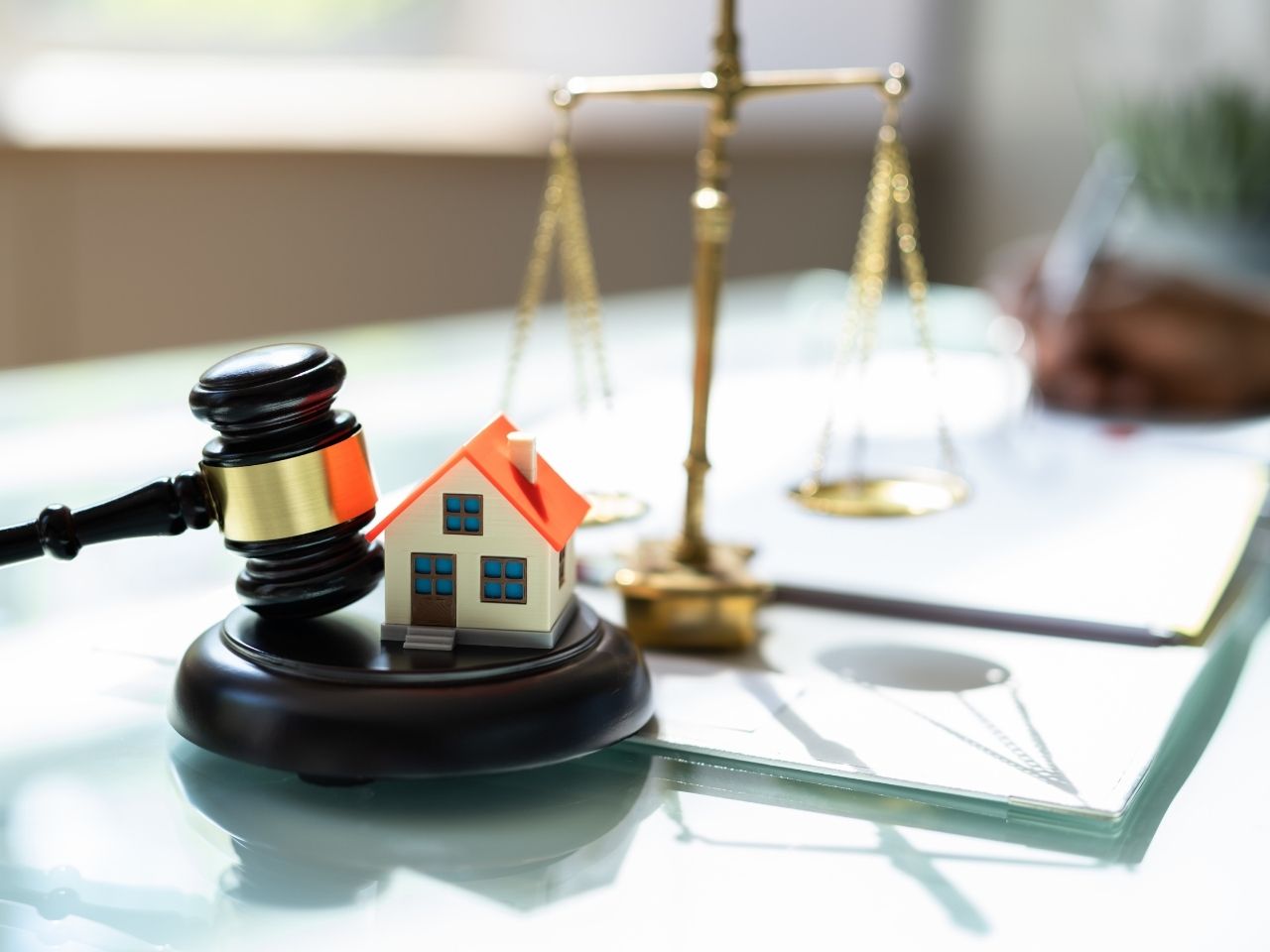 A gavel, miniature house, and weighing scale placed on legal documents, symbolizing NRI property laws and regulatory compliance in Chennai real estate, including RERA, FEMA, and Power of Attorney rules.